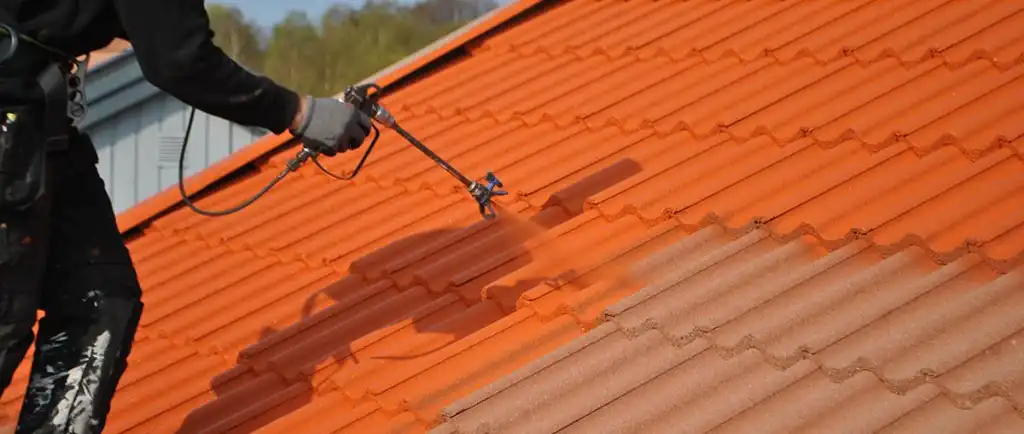 Takmålare sprutmålar ett tegeltak i orange